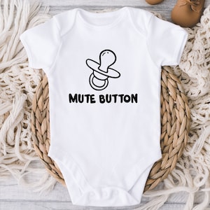 May include: White baby onesie with a black pacifier graphic and the text "Mute Button".