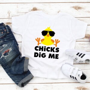 Peut inclure: T-shirt blanc avec un poussin jaune portant des lunettes de soleil et le texte "Chicks Dig Me".