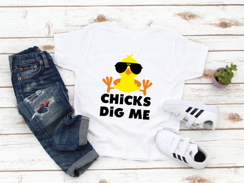Peut inclure: T-shirt blanc avec un poussin jaune portant des lunettes de soleil et le texte "Chicks Dig Me".