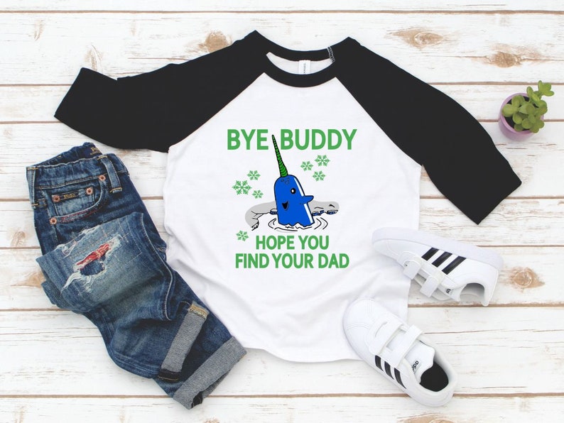 May include: A white and black baseball tee shirt with a narwhal graphic and the text "Bye Buddy Hope You Find Your Dad".