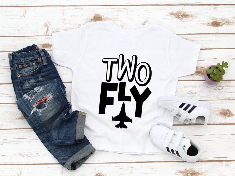 May include: White t-shirt with black text that says "TWO FLY" and a black silhouette of a jet plane.