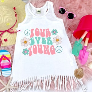 May include: White sleeveless shirt with a fringe hem. The shirt has a graphic design with the text "Four Ever Young" in a retro font with peace signs and flowers.