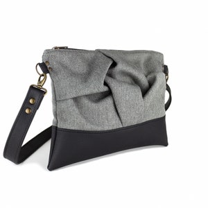 small light grey crossbody bag with hand-smocked pleated detail and black vegan leather bottom and adjustable strap; side view