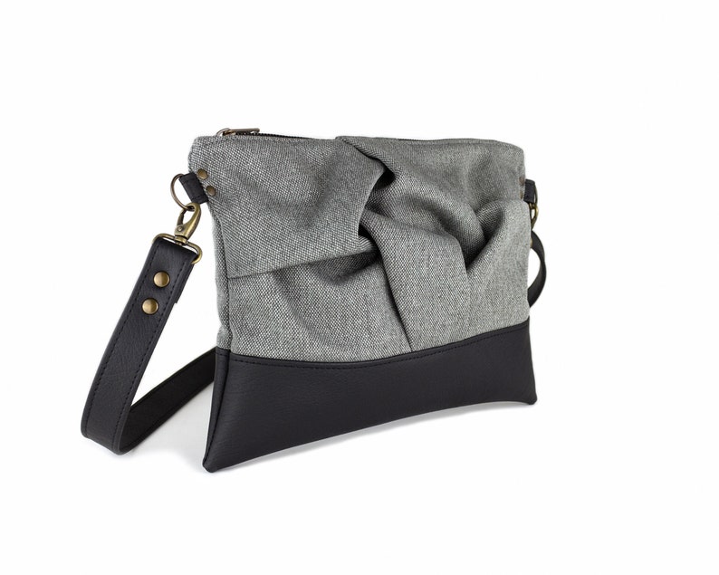 small light grey crossbody bag with hand-smocked pleated detail and black vegan leather bottom and adjustable strap; side view