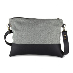 small light grey crossbody bag with hand-smocked pleated detail and black vegan leather bottom and adjustable strap; back view (without pleated detail)