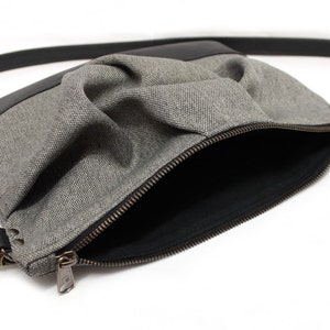 small light grey crossbody bag with hand-smocked pleated detail and black vegan leather bottom and adjustable strap; open