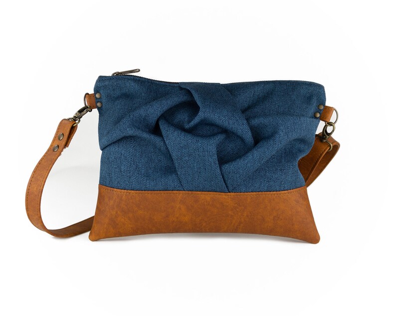 small blue crossbody bag with hand-smocked pleated detail and brown vegan leather bottom and adjustable strap; front view