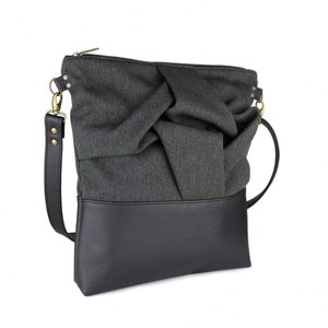 charcoal black medium-sized crossbody bag with hand-smocked pleated detail and  black vegan leather bottom and adjustable strap; side view