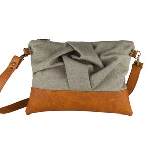 small light brown crossbody bag with hand-smocked pleated detail and brown vegan leather bottom and adjustable strap; front view