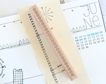May include: A wooden stamp with a hexagonal design and numbers 1 through 31 printed on it. The stamp is used for marking dates on a calendar.