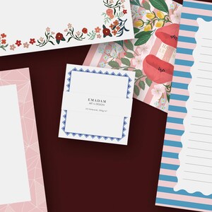 May include: Selection of stationery featuring floral and geometric patterns. Includes a notepad with a blue geometric border, a floral-decorated card, and a striped notepad with a scalloped edge. The stationery uses a variety of colours, including pink, blue, and red.