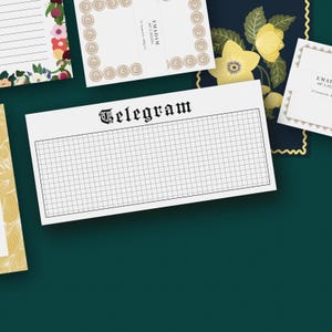 Può includere: Una collezione di articoli di cancelleria, tra cui un blocco note bianco con un motivo a griglia e la parola "Telegram" in un carattere vintage. Altri articoli includono biglietti a tema floreale e biglietti con bordi decorativi. Lo sfondo è verde scuro.