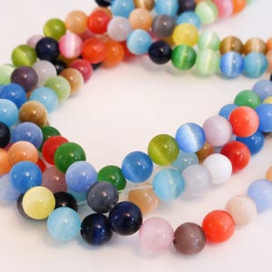 May include: A strand of colorful cat's eye beads. The beads are round and have a smooth, glossy finish. The colors include blue, green, red, yellow, and orange.