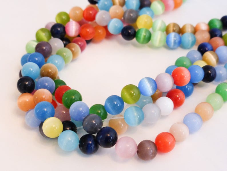May include: A strand of colorful cat's eye beads. The beads are round and have a smooth, glossy finish. The colors include blue, green, red, yellow, and orange.
