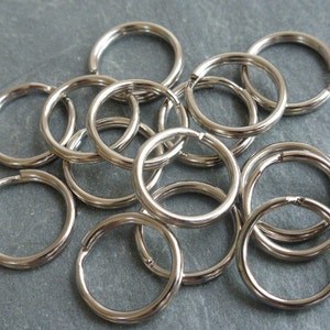 Może przedstawiać: Stos srebrnych breloków do kluczy, wszystkie tego samego rozmiaru, o gładkim, błyszczącym wykończeniu.