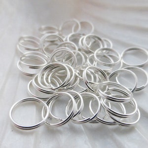 May include: A pile of silver jump rings, a type of jewelry finding used for connecting chains, cords, and other jewelry components.
