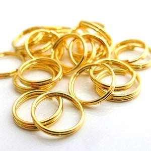 Pode incluir: Um monte de argolas de salto de metal dourado. As argolas são pequenas e redondas, e são perfeitas para prender pingentes, pendentes ou outras peças de joalheria.