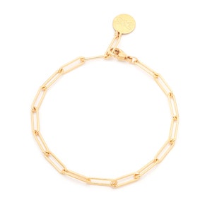 May include: A gold chain bracelet with a small gold charm. The chain is made of interlocking oval links.