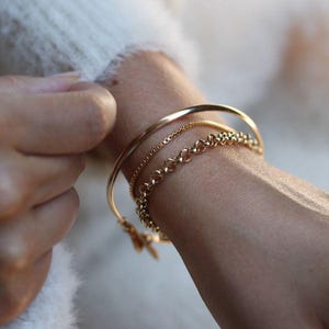 Glamour Bangle in Gold: A classic stacking bangle handmade in Vancouver BC with 14 Karat Gold Fill with adjustable size and dangling charm