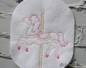 Könnte beinhalten: Eine weiße Filzapplikation eines rosafarbenen Karussells mit einem goldenen Pfosten. Das Pferd ist mit rosa Garn gestickt, der Pfosten mit goldfarbenem Garn. Der Text "Stitched By: I Am Not A Geek Handmade" befindet sich in der rechten unteren Ecke.