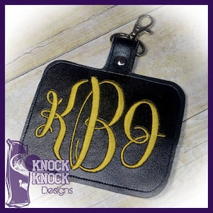 May include: Black leather keychain with a gold embroidered monogram "KBG" and the text "Knock Knock Designs".