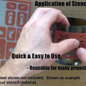 Pu&ograve; includere: Primo piano di una mano che tiene uno stencil su una bottiglia di vetro. Lo stencil &egrave; marrone e presenta un disegno di palma. Il testo "Application of Stencil" e "Quick & Easy to Use" &egrave; visibile nell'immagine. Il testo "Reusable for many projects!" &egrave; anche visibile. Il testo "* Sheet shown not included. Shown as example of our stencil material." &egrave; visibile nella parte inferiore dell'immagine.