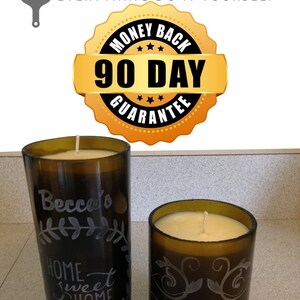 May include: Two glass candle jars with a brown tint. The larger jar has the text "Becca's Home Sweet Home" etched on the side. The smaller jar has the text "The Grove" etched on the side. Both jars have a white candle inside.