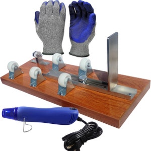 May include: Glass cutting tool with four wheels, a metal guide, and a wooden base. It includes a heat gun and two pairs of gloves, one gray and one blue.