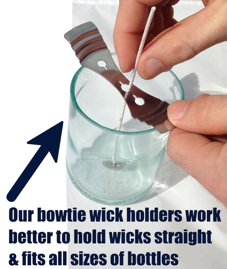 May include: A silver metal bowtie wick holder is being used to hold a white wick straight in a clear glass jar. The wick holder is designed to keep the wick centered in the jar and prevent it from moving around.
