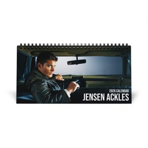 May include: A 2026 calendar featuring Jensen Ackles, with a photo of him driving a car. The calendar has a spiral binding at the top and the text "2026 Calendar" and "Jensen Ackles" in white.