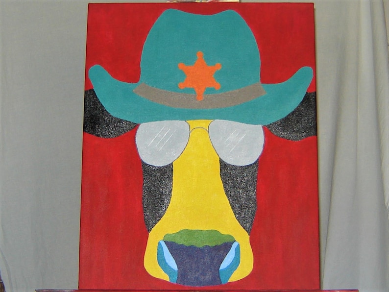 May include: A painting of a cow wearing a blue and green cowboy hat with a yellow star on the front. The cow's eyes are covered by silver sunglasses. The background is red.