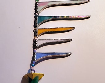 Könnte beinhalten: Ein Buntglas-Sonnenfänger mit einer Reihe von bunten, gebogenen Glasstücken, die an einer Perlenkette hängen. Der Sonnenfänger hat ein grün-gelb-blaues Farbschema.