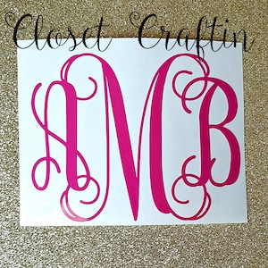 May include: A bright pink vinyl decal featuring a large, ornate, three-letter monogram with the letters A, M, and B in a decorative script font. The decal is applied to a white rectangular backing sheet with the text Closet Craftin above it.