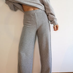 May include: Gray wide-leg pants made from a soft, knit fabric. The pants have a high waist and a relaxed fit.