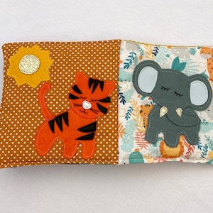 May include: A brown and orange fabric book with a tiger and a sun on one side and an elephant and jungle leaves on the other side.