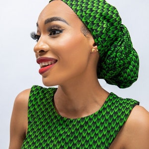 May include: A green and black patterned head wrap and matching sleeveless top. The fabric features a repeating design of green leaf-like shapes on a black background. The head wrap is styled in a bun, and the top has a scoop neckline.