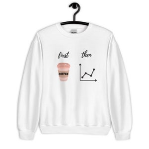 May include: White sweatshirt with the text "first then" above a coffee cup graphic and a line graph. The coffee cup is light brown with a pink lid and the word "COFFEE" printed on it. The line graph is black.