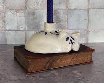 Candelabro de cerámica vintage con forma de gato durmiendo, arte popular azul y blanco, con marca del fabricante.