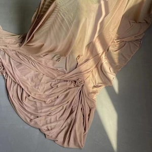 May include: A soft, light pink fabric backdrop with a smooth, silky texture. The fabric is draped and folded, creating a flowing, elegant look.