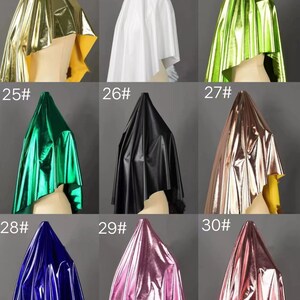 May include: Nine samples of metallic fabric in different colors, including gold, white, green, black, rose gold, pink, and blue. Each fabric sample is draped over a mannequin head.