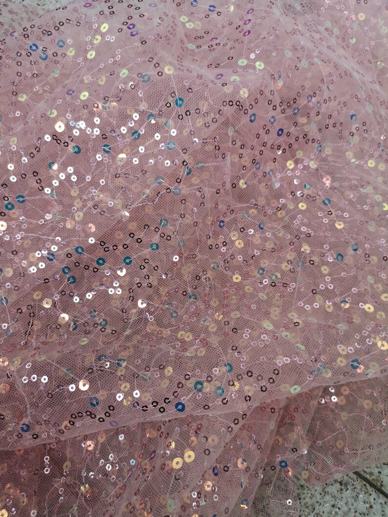 May include: Pink sheer fabric with iridescent sequins. The sequins are scattered randomly across the fabric.