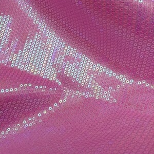 Op de afbeelding: Roze stof met iriserende pailletten in een cirkelvormig patroon.