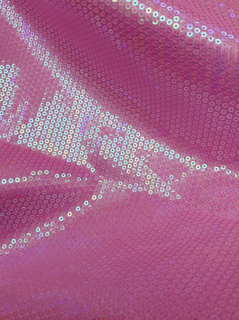 Op de afbeelding: Roze stof met iriserende pailletten in een cirkelvormig patroon.