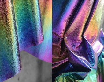 May include: Close-up of iridescent fabric with a textured surface. The fabric is folded and has a rainbow sheen.