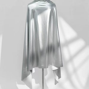 May include: A silver metallic fabric draped over a mannequin. The fabric is smooth and shiny, with a slight sheen.