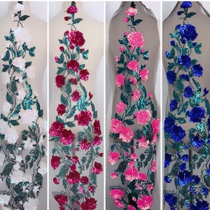 Può includere: Quattro pezzi di tessuto con paillettes con motivi floreali. Il tessuto è bianco, rosa, fucsia e blu.