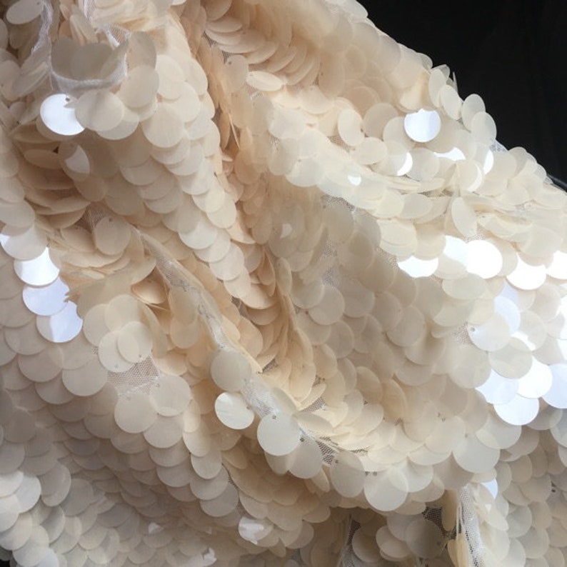 Puede incluir: Tela de color crema con lentejuelas grandes y redondas. Las lentejuelas est&aacute;n cosidas sobre una tela de malla transparente.