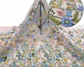 May include: A sheer, light-colored fabric with embroidered floral designs in shades of blue, pink, yellow, and green. The flowers are raised and have a 3D effect.
