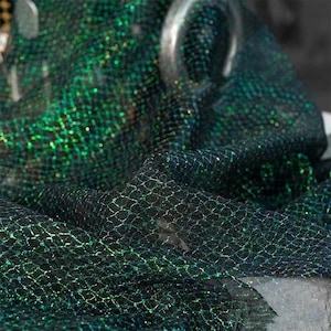 May include: Green iridescent mesh fabric with a diamond pattern. The fabric is sheer and has a slight shimmer.
