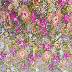 Puede incluir: Una tela transparente con un intrincado patrón de bordado floral en tonos melocotón, lavanda, verde lima y fucsia brillante. El diseño está acentuado con pequeñas lentejuelas reflectantes dispersas por los motivos florales sobre una base de malla.